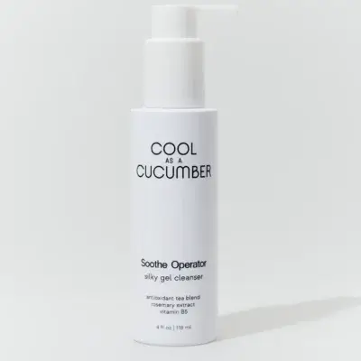 White minimalist skincare bottle with pump, label reads 'COOL AS A CUCUMBER' and 'Soothe Operator silky gel cleanser' against a light background