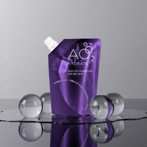 Purple stand-up pouch of Hydrate skincare product labeled A02 on a reflective surface, surrounded by clear glass spheres.
